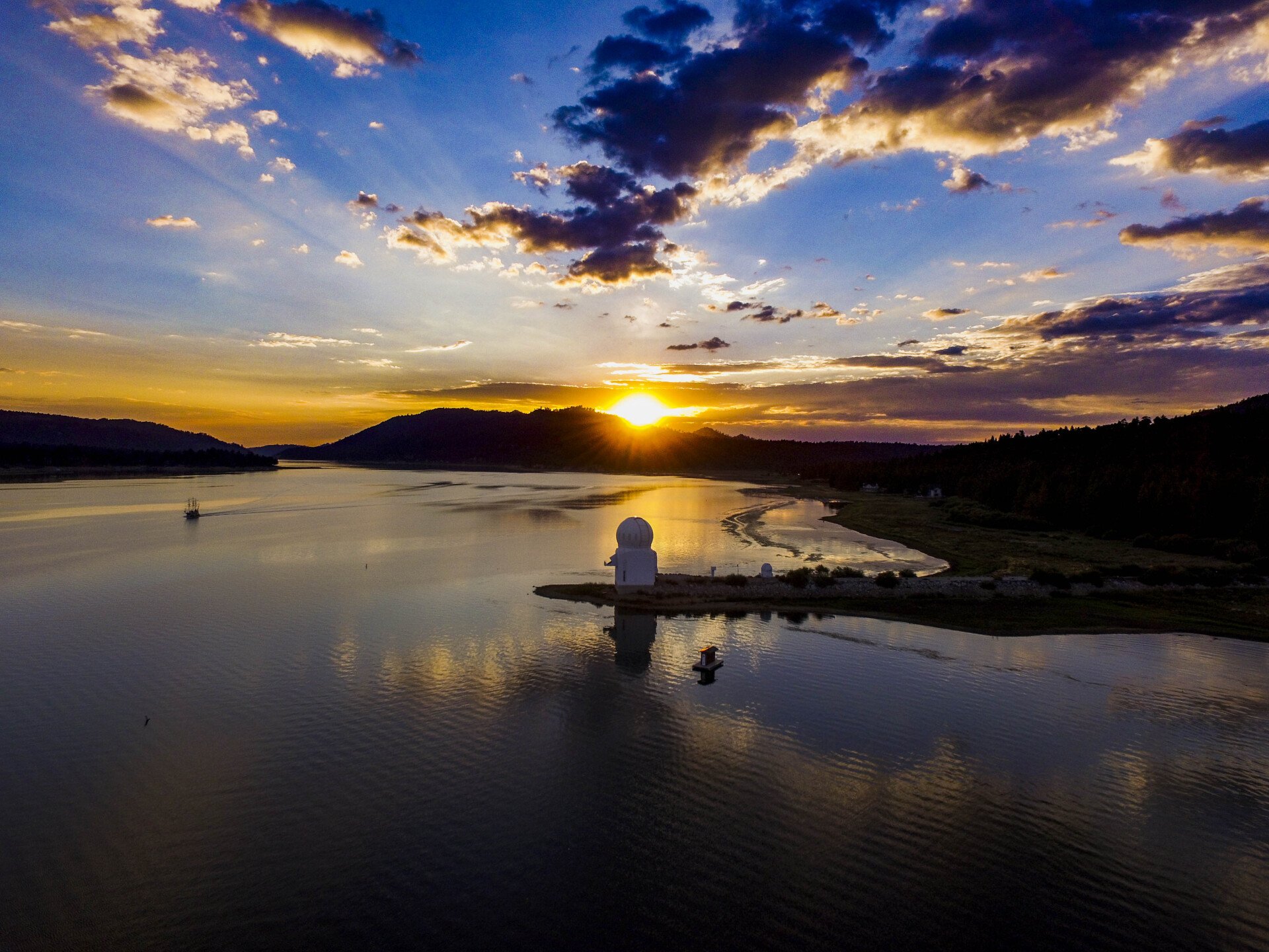 Aerial view of Big Bear Lake at sunset, with the solar observatory and the Pirate Ship on the water