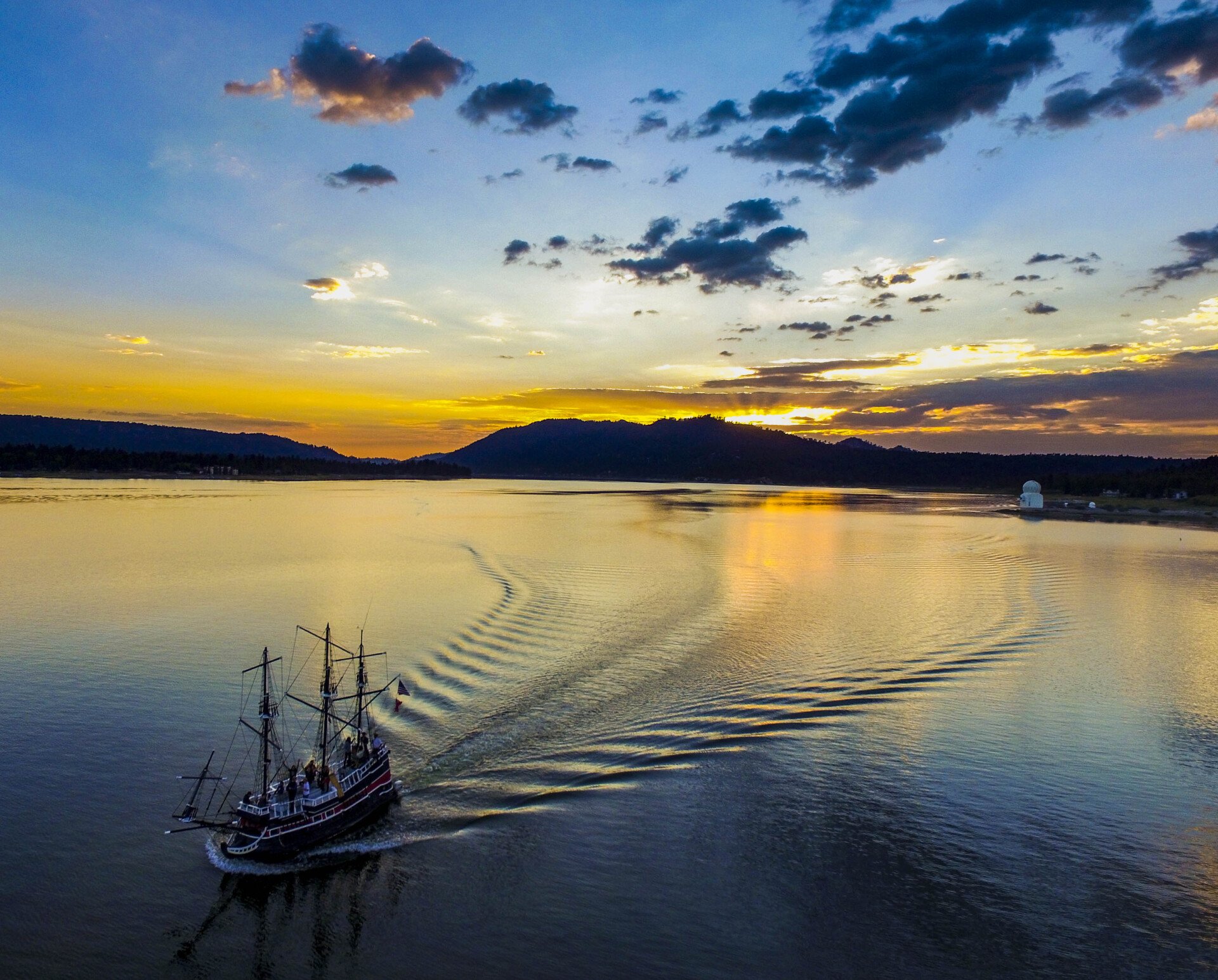 The Pirate Ship cruising Big Bear Lake at golden hour with guests on deck
